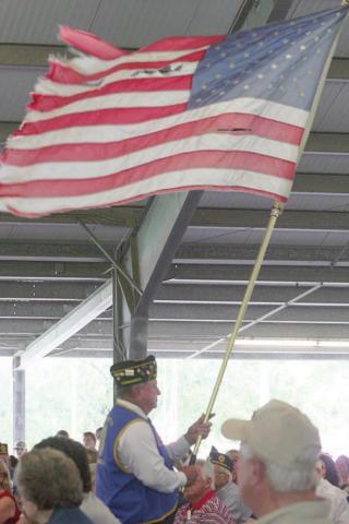 Bob Heinrich walks a tattered flag through the crowd while the song “Ragged Old Flag” by Johnny Cash plays. Sticker Photo By Darrell Vyvjala