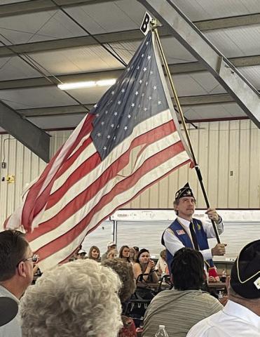 Post 143 First Vice Commander Ed Semler waves a tattered flag while the song “Ragged Old Flag” by Johnny Cash plays. Sticker Photo By Darrell Vyvjala