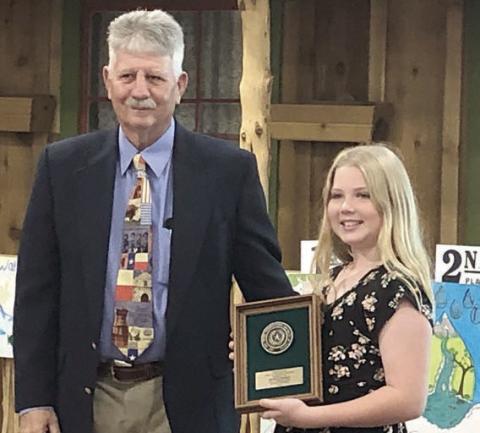 Brynlee Berger (right) of Schulenburg received a plaque for placing third in the poster contest held as part of the Texas Conservation Awards Program. The presenter was Leroy Wolff (left), Area 3 director for the Association of Texas Soil &amp; Water Conservation Districts (ATSWCD).