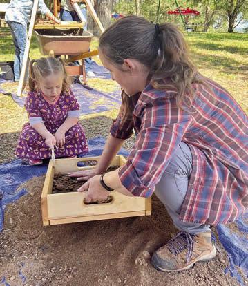 Sifting for archeological artifa cts at a previous Archeology Day’s mock excavation is a member of the Texas Historical Commission staff demonstrating the process to a youngster in attendance.
