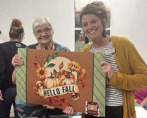 The lucky blackout BINGO prize winner of a fall-themed door mat from Chyla Podhajsky (right) and Wellsential was Cynthia Meyer (left).