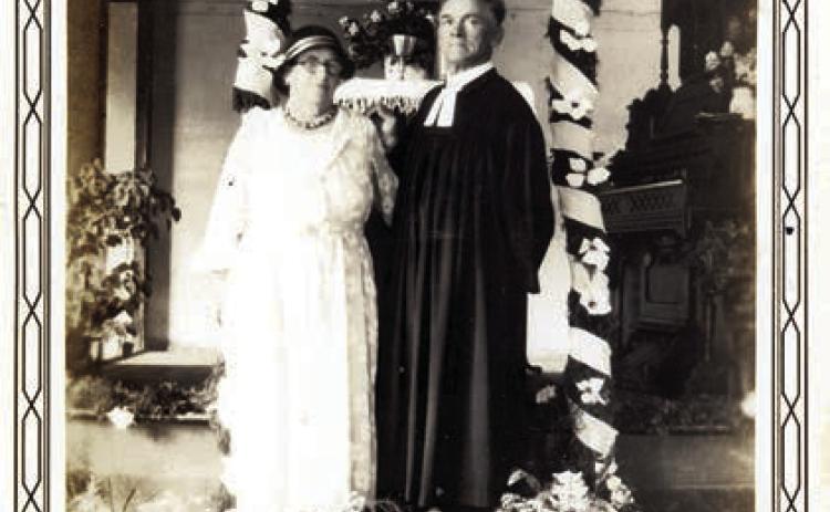 Minna and Rev. Carl Baer standing under a decorated arch in 1935. – Courtesy of Fayette Heritage Museum &amp; Archives
