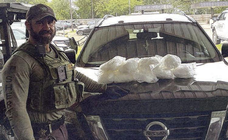 Deputy Cody Williams is shown with the nine bundles believed to contain methamphetamine that were seized following a traffic stop on the Nissan SUV. Photo Courtesy of Fayette County Sheriff’s Department