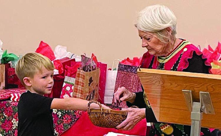 During the white elephant gift exchange, Dominik Woodworth (left) performs the drawing for who is next to choose a gift as Betty Danner holds the basket.