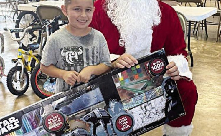 A young man poses with Santa (Investigator Jeremy Castleberry) during last year’s toy pick-up in Flatonia.
