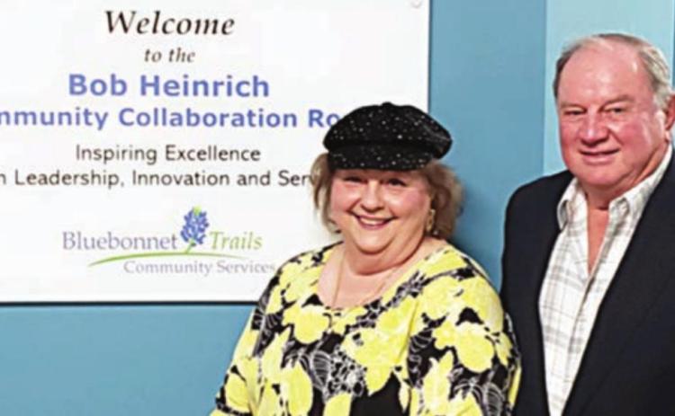 BOB HEINRICH COMMUNITY COLLABORATION ROOM – Robert L. “Bob” Heinrich and his wife Diana stand beside the sign that designates a room at the new Bluebonnet Trails Community Service building in his honor.