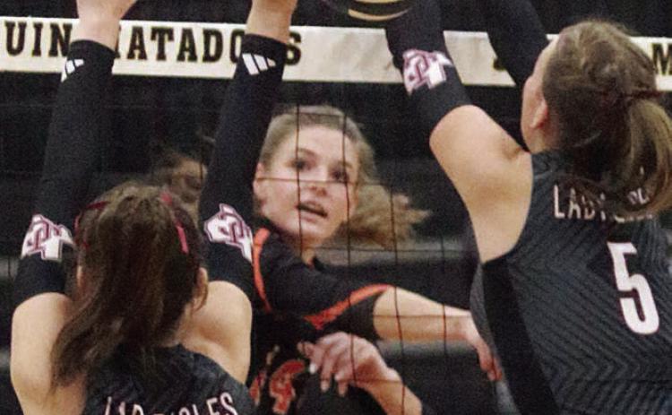Emmrie Marx fires a kill in between two Johnson City blockers in the second set. Sticker Photo By Darrell Vyvjala