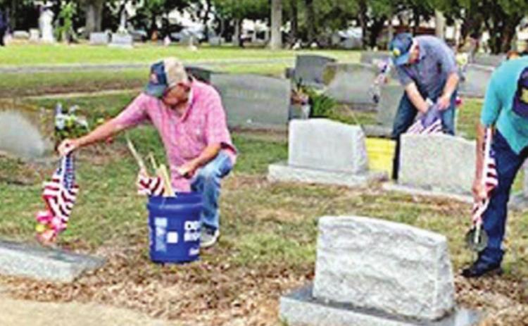 From left: C.W. Leonard, Wesley Holub, Delvin Dieringer and Stanley Kubenka mark the graves of deceased veterans with flags at the Schulenburg City Cemetery.
