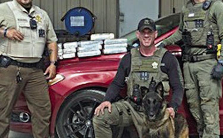 From left: Deputy Herman Olvera, Drug Interdiction Sgt. Randy Thumann and K-9 Kolt, and Drug Interdiction Investigator David Smith are shown with the 11 kilos of cocaine they seized on May 16.