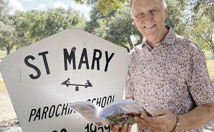 Willy Schmidt shared his memories of attending St. Mary Parochial School at High Hill, along with his classmate and childhood neighbor Cleo Dittrich Wenske, in Stories I’ve Been Told – Volume 4. He expects his story to live on for generations and become a family heirloom. Willy is pictured taking his first look at the book beside the sign marking the location of his first school.