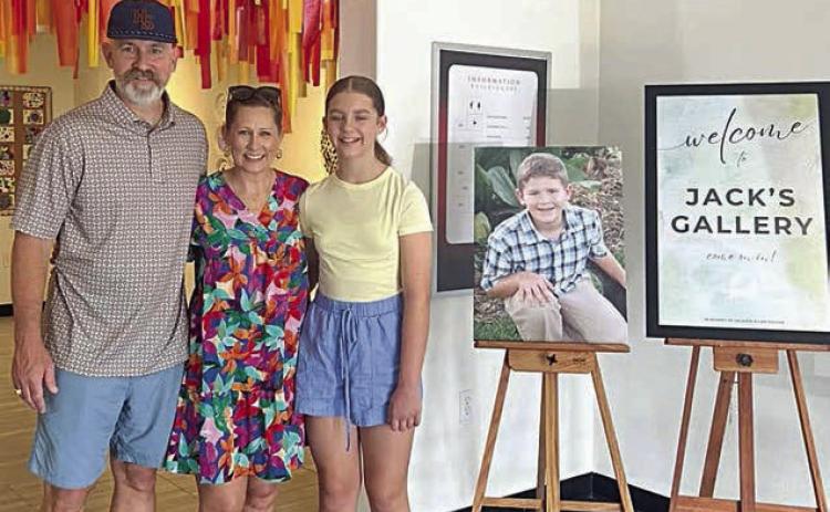 Turtle Wing Foundation was established in honor of Jack Hooper, son of Chris and DeeAnn Hooper. Jack, who had been diagnosed with high-functioning autism at age 6, passed away on April 5, 2011. Shown are (from left) Chris and DeeAnn Hooper and their daughter Cate Hooper. A portrait of Jack Hooper is placed between the family and the Jack’s Gallery sign.