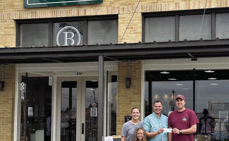 Schulenburg Economic Development Corporation President Paddy Magliolo (right) presents a $7,500 grant to Kevin, Megan, and Hannah Bartos. Bartos Investments, LLC applied for the beautification grant for the Bartos’ recently-opened business, Country Oak Boutique, at the corner of North Main Street and Wolters Avenue.