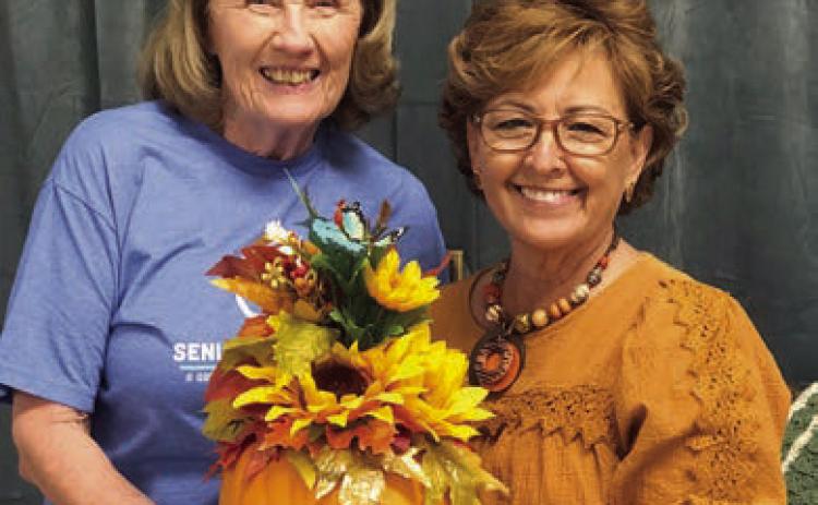 ABOVE – Helping to welcome fall with a blackout bingo prize she created is Martha Beckmann (right). Sharon Rodriguez (left) was the lucky winner.