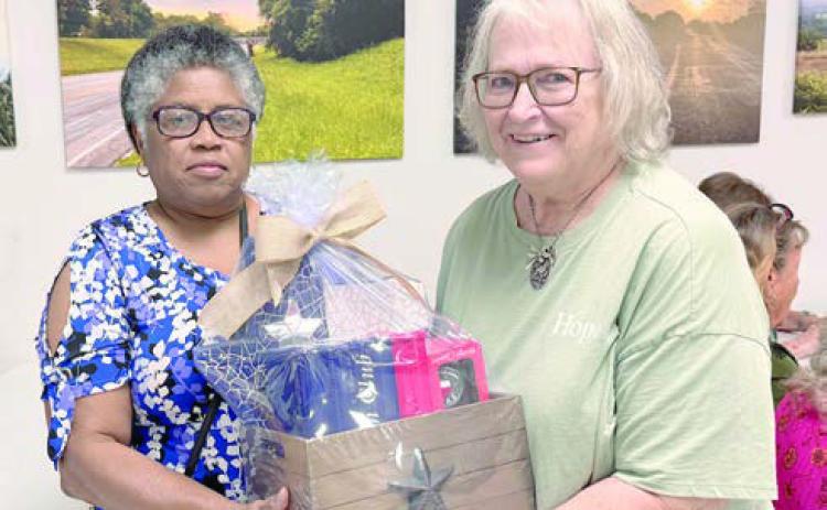 Talented artist and member Janice Collins (left) assembled this gift basket featuring a Texas-shaped mosaic that she created, a bottle of Texas Crown Whiskey and two commemorative glasses. A drawing was held, won by Carolyn Foster (right). The drawing raised $740, with all the funds going to the building capital campaign.