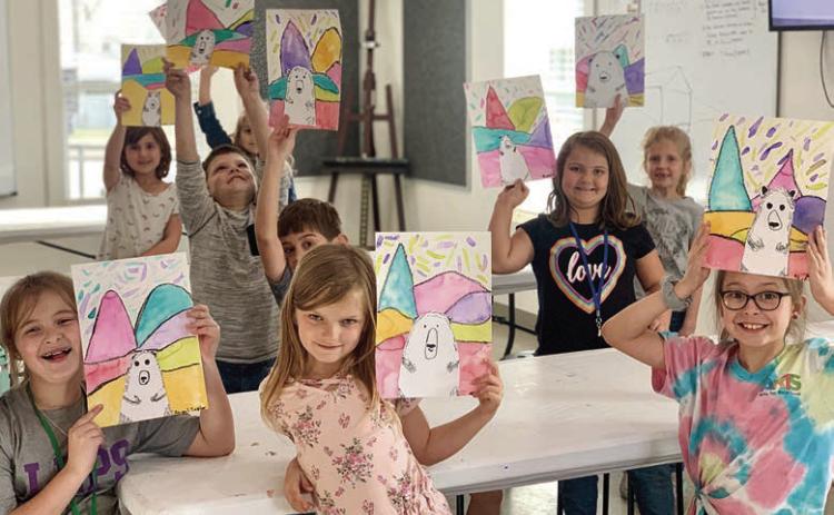 In the Arts for Rural Texas art after-school program at the Fayetteville campus, students display artwork created during a previous session. In this lesson, the students learned about artist Ted Harrison and created work inspired by his bright and colorful landscape paintings of the Yukon.