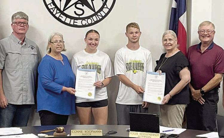 The Schulenburg City Council presents proclamations recognizing Schulenburg High School senior Mikayla Otto and sophomore Caden Herzik (center) for making the Class 2A state tennis tournament as a mixed doubles team. Shown with Otto and Herzik at Monday night’s meeting are: (from left) aldermen Greg Thomas and Frank Wick III, Mayor Connie Koopmann; and (from right) aldermen Clarence Ahlschlager, Roger Moellenberndt, and Kathy Kleiber. Sticker Photo By Darrell Vyvjala