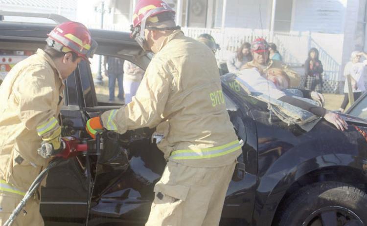 Firefighters use extrication tools to remove the door of the vehicle from which Katry Kobza was ejected through the windshield and later pronounced “deceased.” Sticker Photo By Darrell Vyvjala