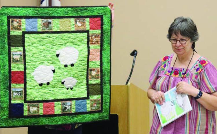 LEFT PHOTO – Sandy Courrier shows her quilt constructed to accompany the children’s book Cheepy and Grandma Mare.