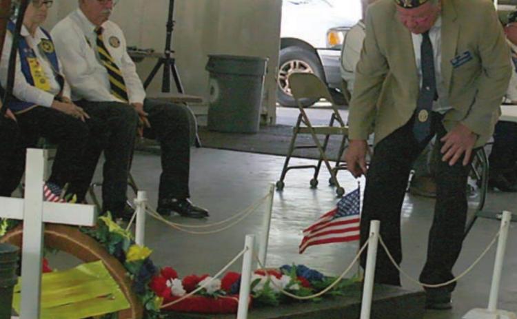 American Legion McBride Post 143 Commander Bob Heinrich places a flag on the “Grave of the Unknown Soldier.” Sticker Photo By Darrell Vyvjala