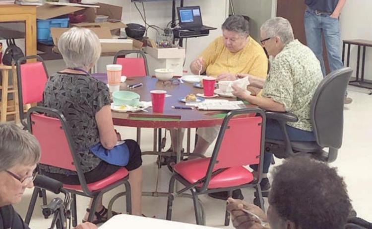 SPEAKER – Kevin Raabe (standing at back right), plant manager at Dairy Farmers of America, gave a presentation at NVCC. Members seated at the table in the foreground are Jo Nell Vacek on the left and Freda Ellison on the right.