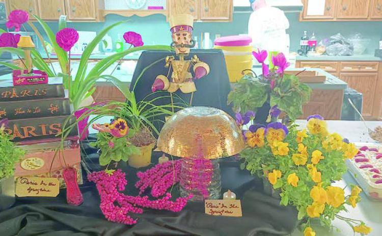 AT LEFT – Hoste sses for the Garden Club meeting were (seated) Billie Rightmer, (standing, from left) Gail Hammontree and Jerry Leonard. cente rpiece reflected the decoration theme, “Paris in the Springtime.” ABOVE – The
