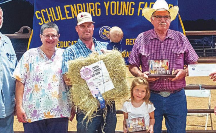 Reserve champion - Kutac Farms with an entry of coastal bermudagrass hay. The bale sold for $900 and buyers were Moeller Custom Lawn Mowing & Shredding, Bubela Tree Service & Arbor Care and Weimar Vet Clinic. La Grange Farm & Ranch donated 1,000 lbs. of fertilizer to the winner. Shown are (from left) Ed and Jennifer Moeller of Moeller Custom Lawn Service; Aaron Kutac, Allen Kutac, Ainsley Kutac and A.J. Kutac of Kutac Farms; and Mark Vecera of the Young Farmers. Photo By Andy Behlen/Fayette Co. Record