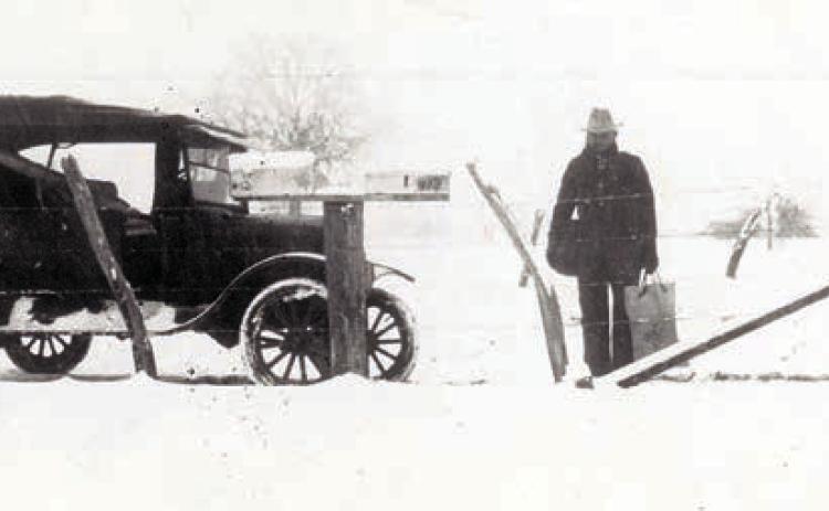 A mail carrier, possibly John Giese, is shown holding a mail bag and pouch after the Jan. 23, 1926, snowfall.