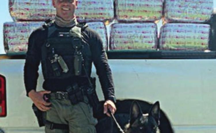 Sgt. Randy Thumann and his K-9 partner, Kolt, with the 253 pounds of marijuana they discovered Monday.