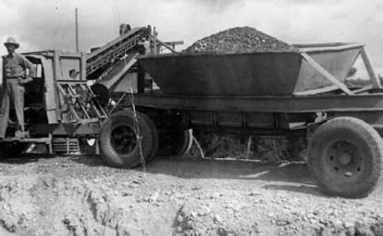 Photograph of an unidentified man standing on the running board of a gravel truck. Courtesy of Fayette Heritage Museum &amp; Archives