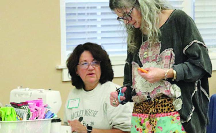 Cutting a strip for Lisa Sandlin (left) is Michelle Lavender (right).