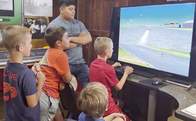 Volunteer Zuriel Robles (third from left) guides the co-pilots on the Real Flight Simulator.