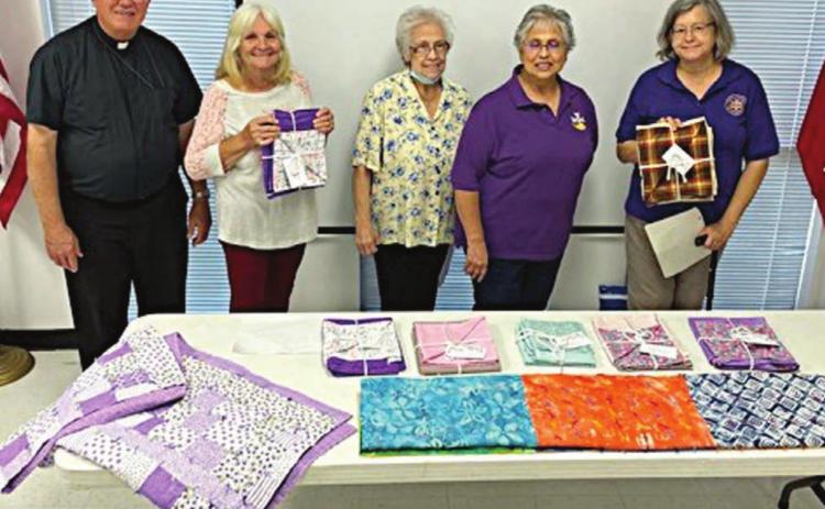 SHOWN WITH PRAYER BLANKETS being constructed in a program recently undertaken by Catholic Daughters Court St. Rose 1597 are (from left) chaplain Rev. Tim Kosler and volunteers Clara Clark, Pat Christ, Rosa Galipp and Karen Miley.