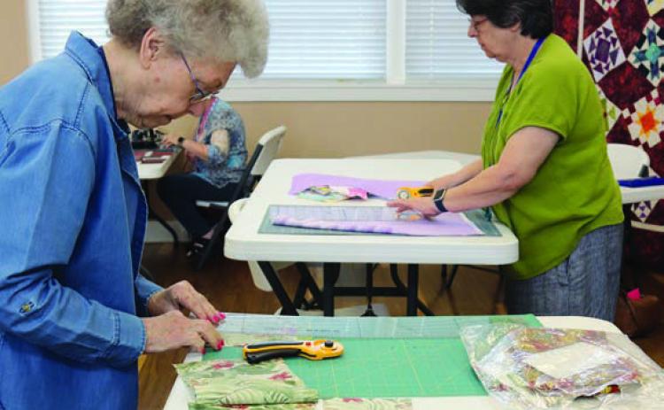 Cutting quilt blocks are Kay Marburger and Kathi Babcock.