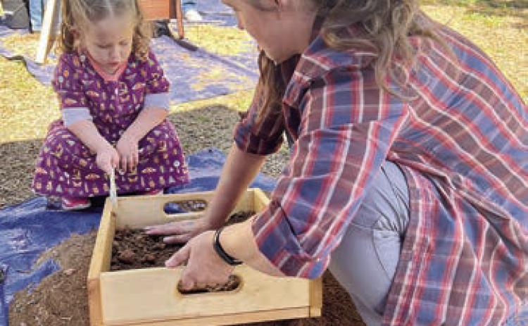Sifting for archeological artifa cts at a previous Archeology Day’s mock excavation is a member of the Texas Historical Commission staff demonstrating the process to a youngster in attendance.