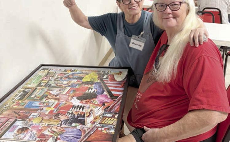 Showing off the puzzle that was completed after many hours of work by many people are (from left) volunteer Brenda Ray and member Kelly Ortiz.