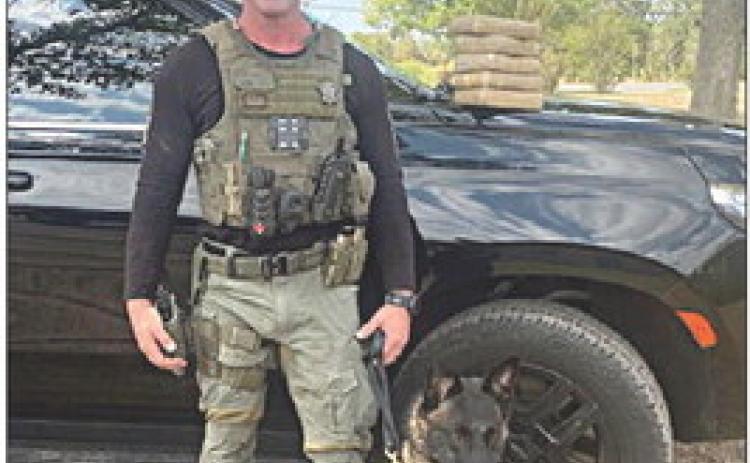 Sgt. Randy Thumann and his canine partner, Kolt, are shown with the packages of cocaine they discovered following a traffic stop on I-10 Sunday.